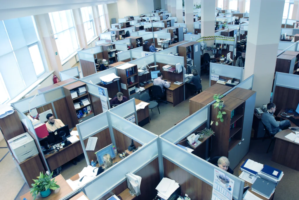 Vista de cima de um grande escritório com baias, com dezenas de pessoas trabalhando em seus computadores