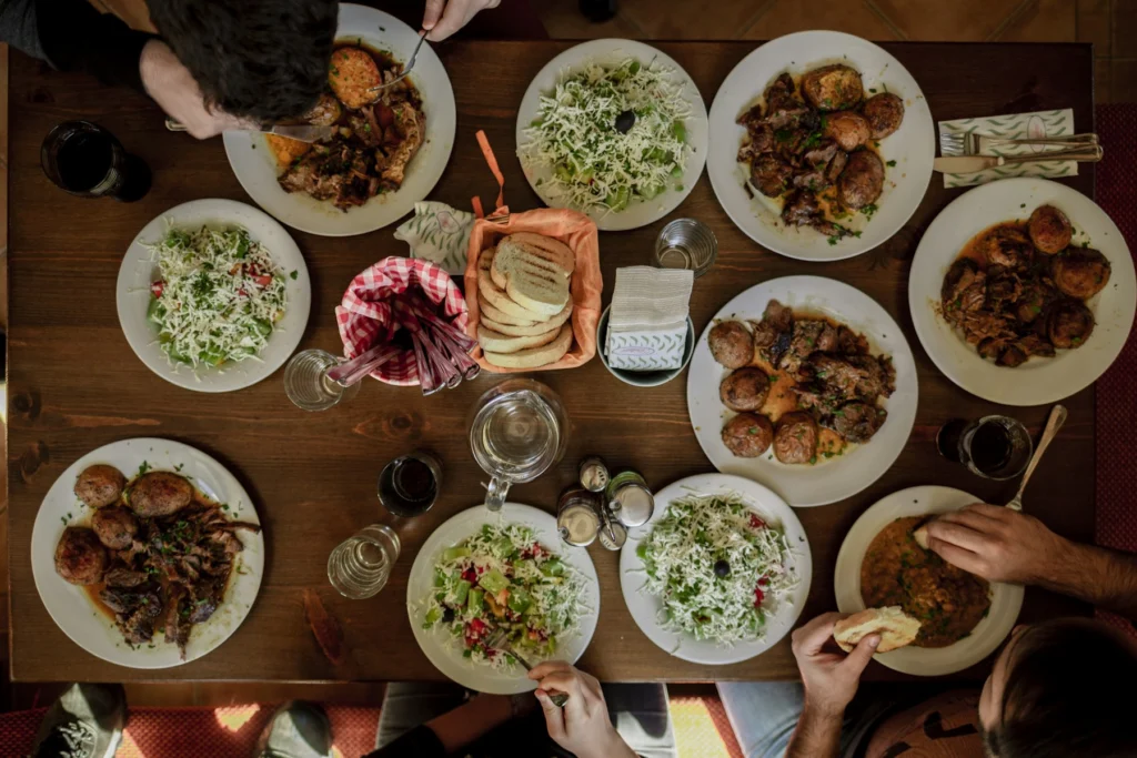 Mesa de refeição vista de cima, com pratos e mãos servindo
